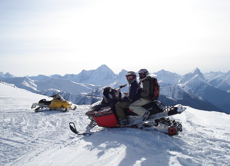 2 people sharing a snowmobile on the top of a mountain at Kicking Horse