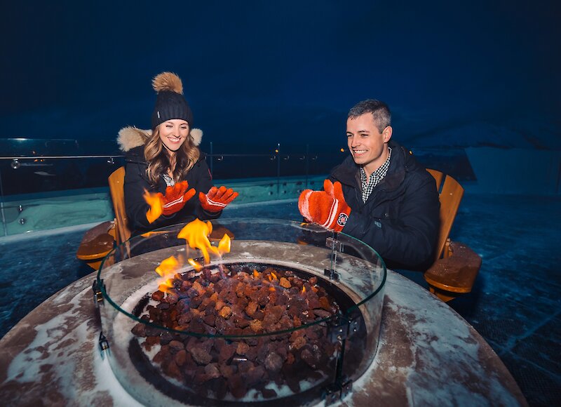 Warming by the fire at the top of the Banff Gondola at night