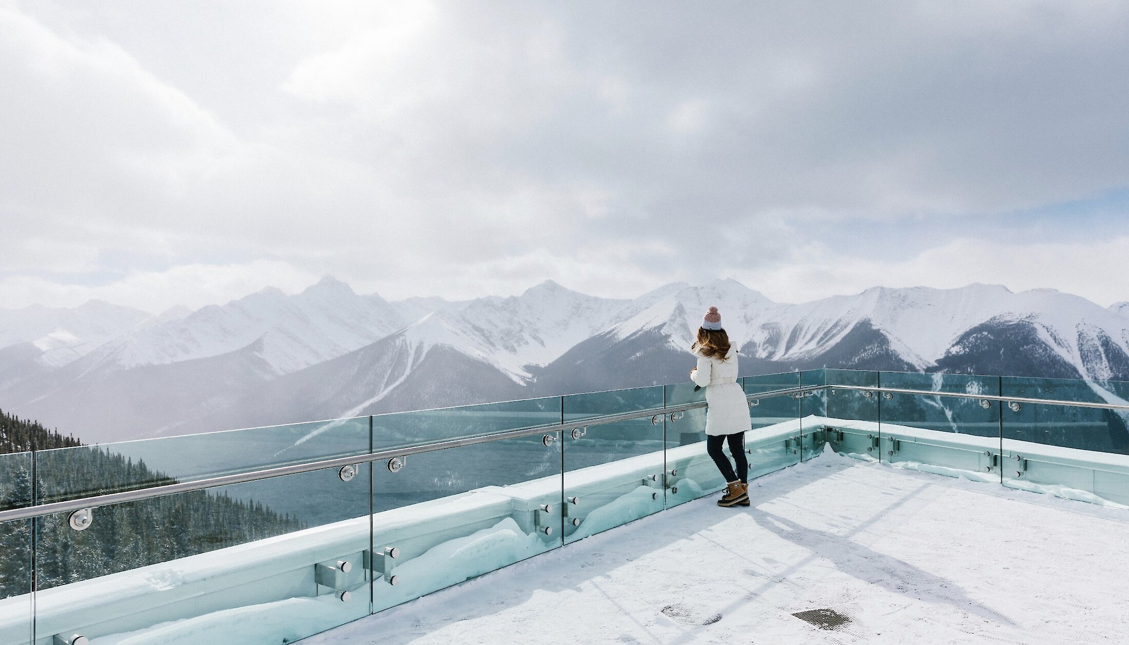 A lady on the viewing deck of the Banff Gondola in Winter taking in the mountain views