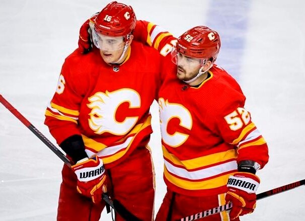 Two Calgary Flames hockey players hugging on the ice at the Scotiabank Saddledome in Calgary