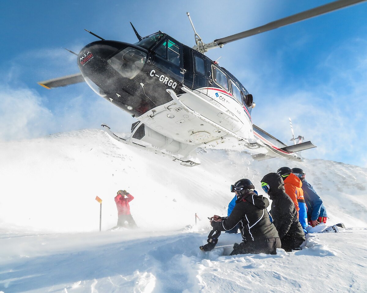 Guests watching the helicopter depart on a heliskiing adventure