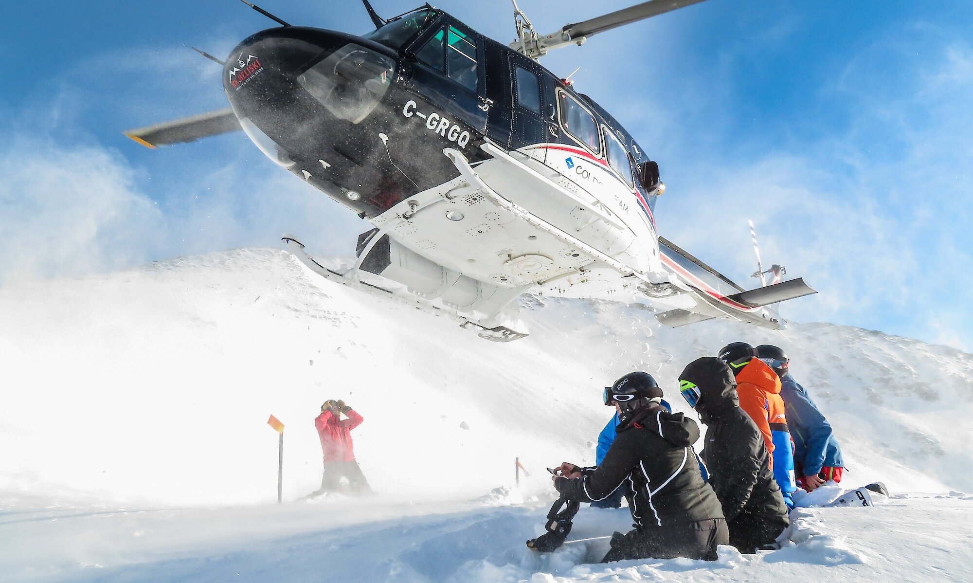 Guests watching the helicopter depart on a heliskiing adventure