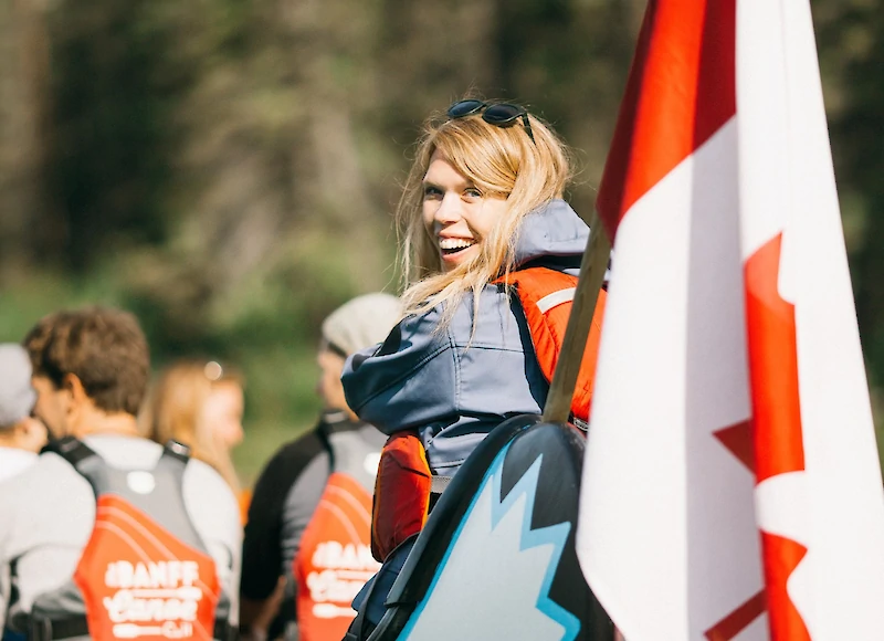 A smiling tour guide steering the Big Canoe Tour in Banff