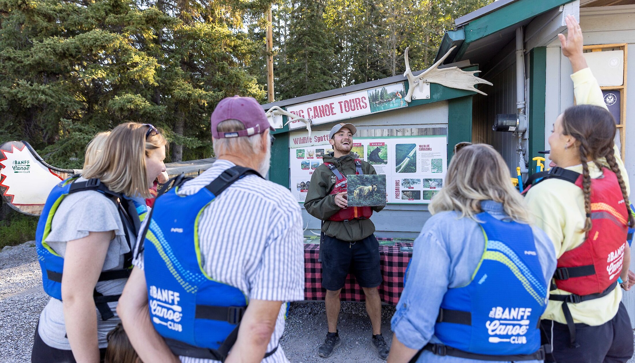 People listening to a tour guide giving an interpretive talk at the Banff Canoe Club before a Big Canoe Tour