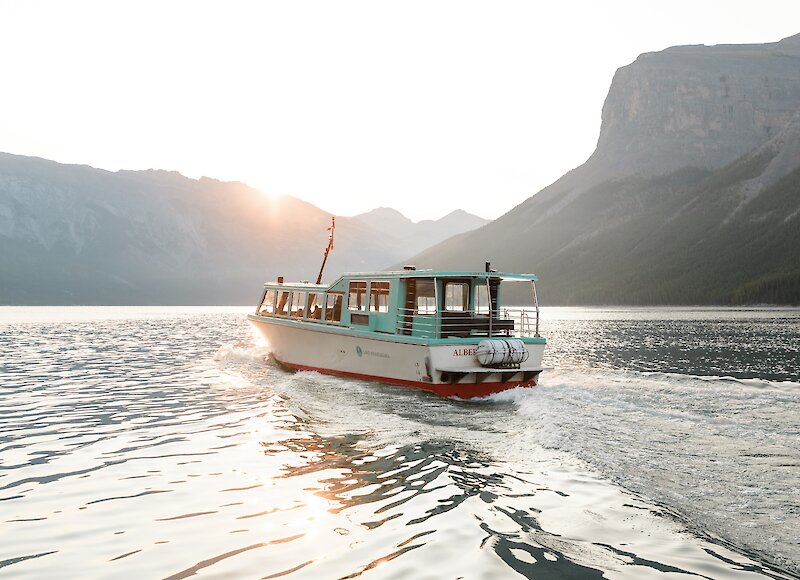 A boat cruise on lake minnewanka with the sun setting over the mountains in Banff