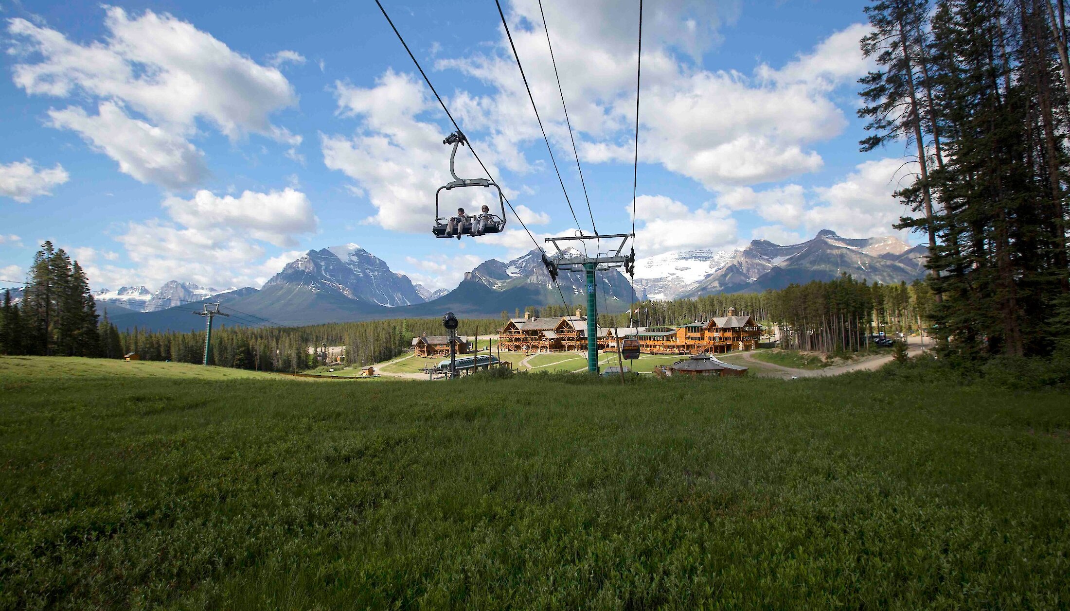 The Lake Louise sightseeing chairlift going over the green grass
