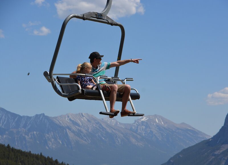 A man and little girl on the Mount Norquay Chairlift taking in the spectacular mountain views.