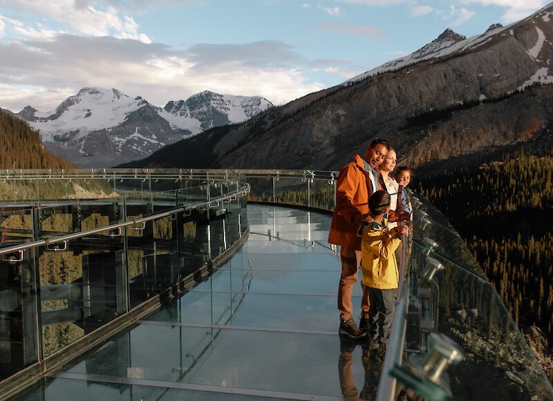 A family on the Skywalk glass bottom bridge at the Columbia Icefields looking out at the Canyon
