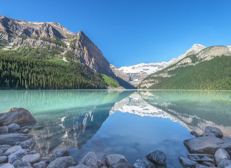 A view of Lake Louise from the shoreline in Banff National Park on a sunny day