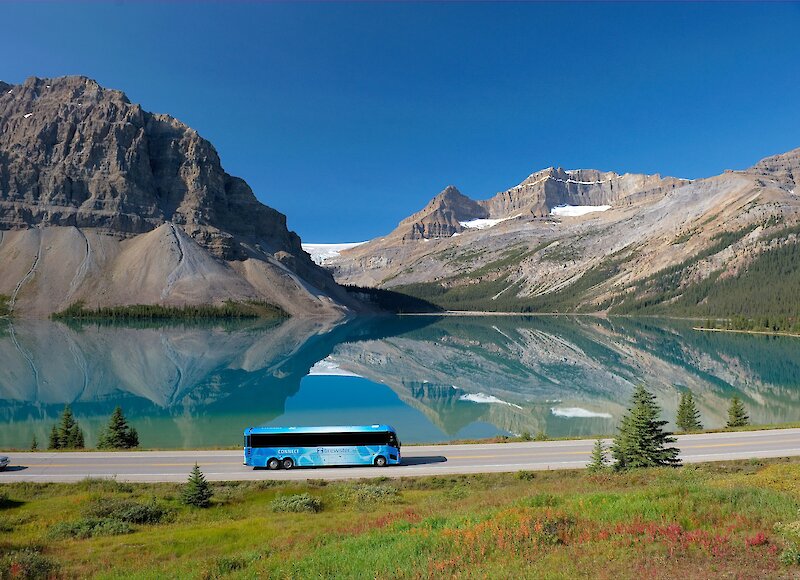 A tour bus driving along the Icefields Parkway on a sunny bluebird day