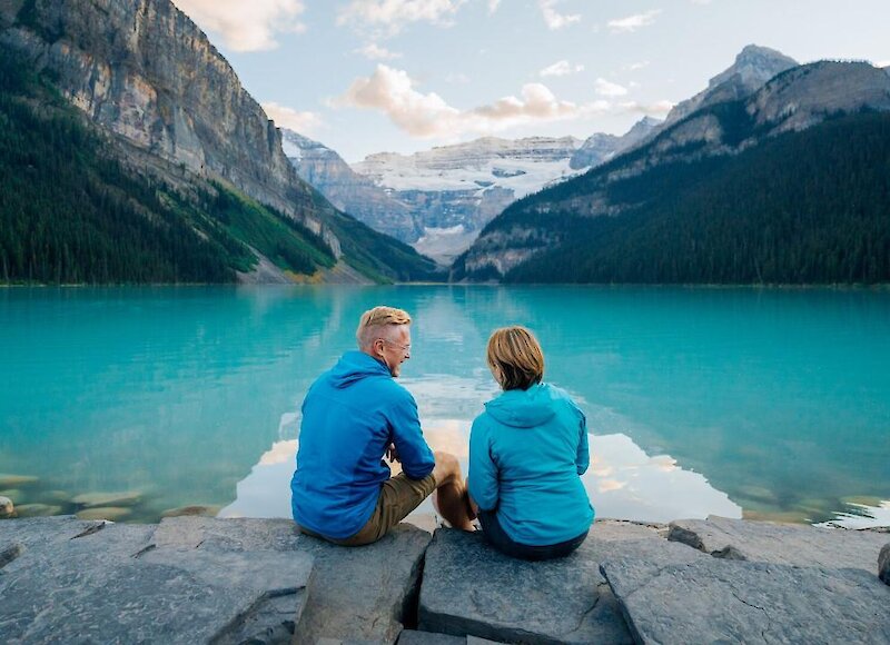 A couple sitting on the shoreline of Lake Louise enjoying the mountain views