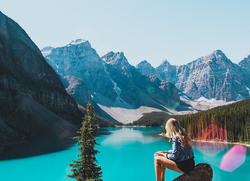 A girl on the top of the rockpile taking in the views of the turquoise moraine lake