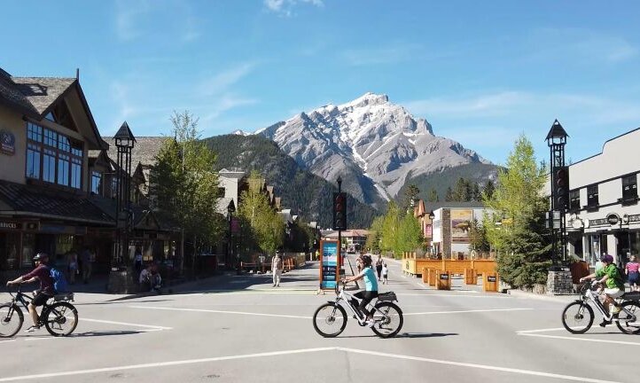 People cycling Ebikes on Banff Ave in front of Cascade Mountain