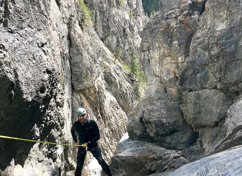 A man walking up a canyon holding a rope on a canyon tour