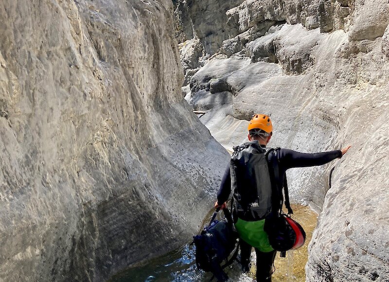 A man walking through water on a canyon tour