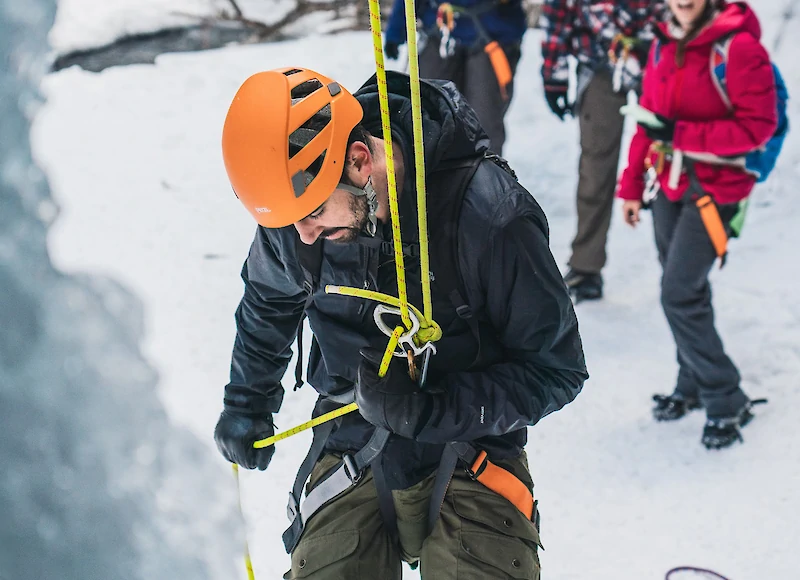 A group watching a guest rapel from the base of the canyon
