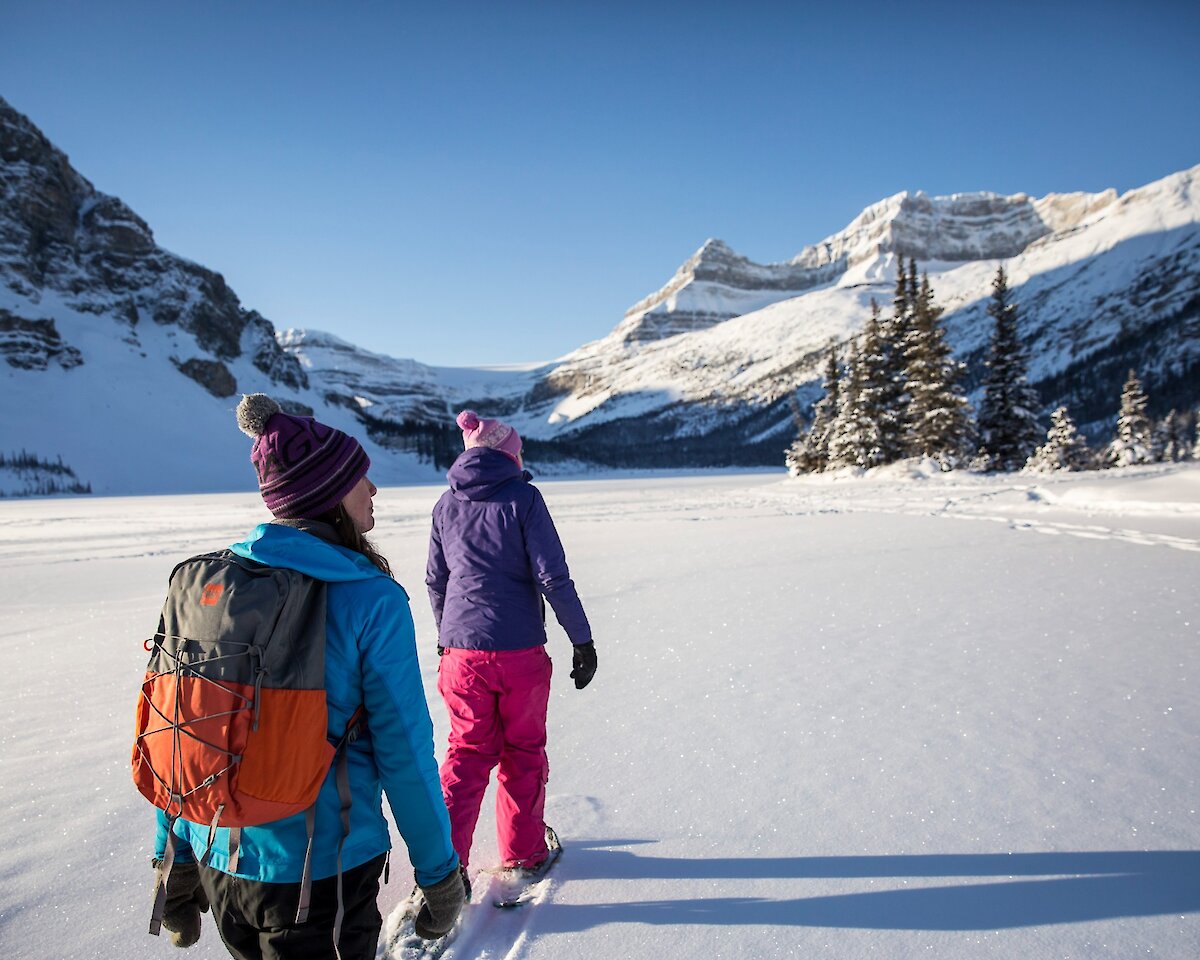 Friends snowshoeing on a frozen lake on the Icefields Parkway in Banff